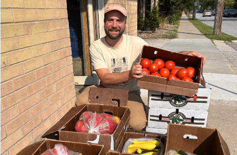  Will Moyer the Food Hub Manager at Argus Farm Stop stands behind several boxes of produce